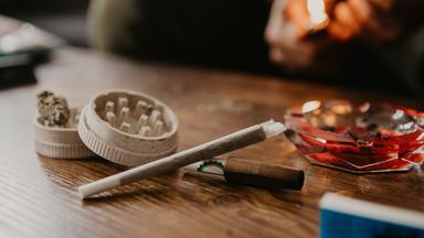 Ein Joint mit Cannabis und Aschenbecher im Hintergrund.