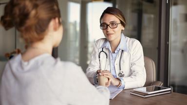 Eine Ärztin hält die Hand eines Patienten.