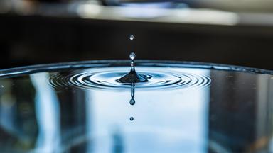 Ein Wassertropfen trifft auf eine Wasseroberfläche