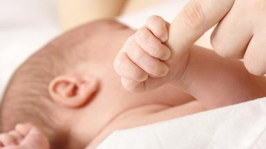 Säugling greift nach der Hand seiner Mutter