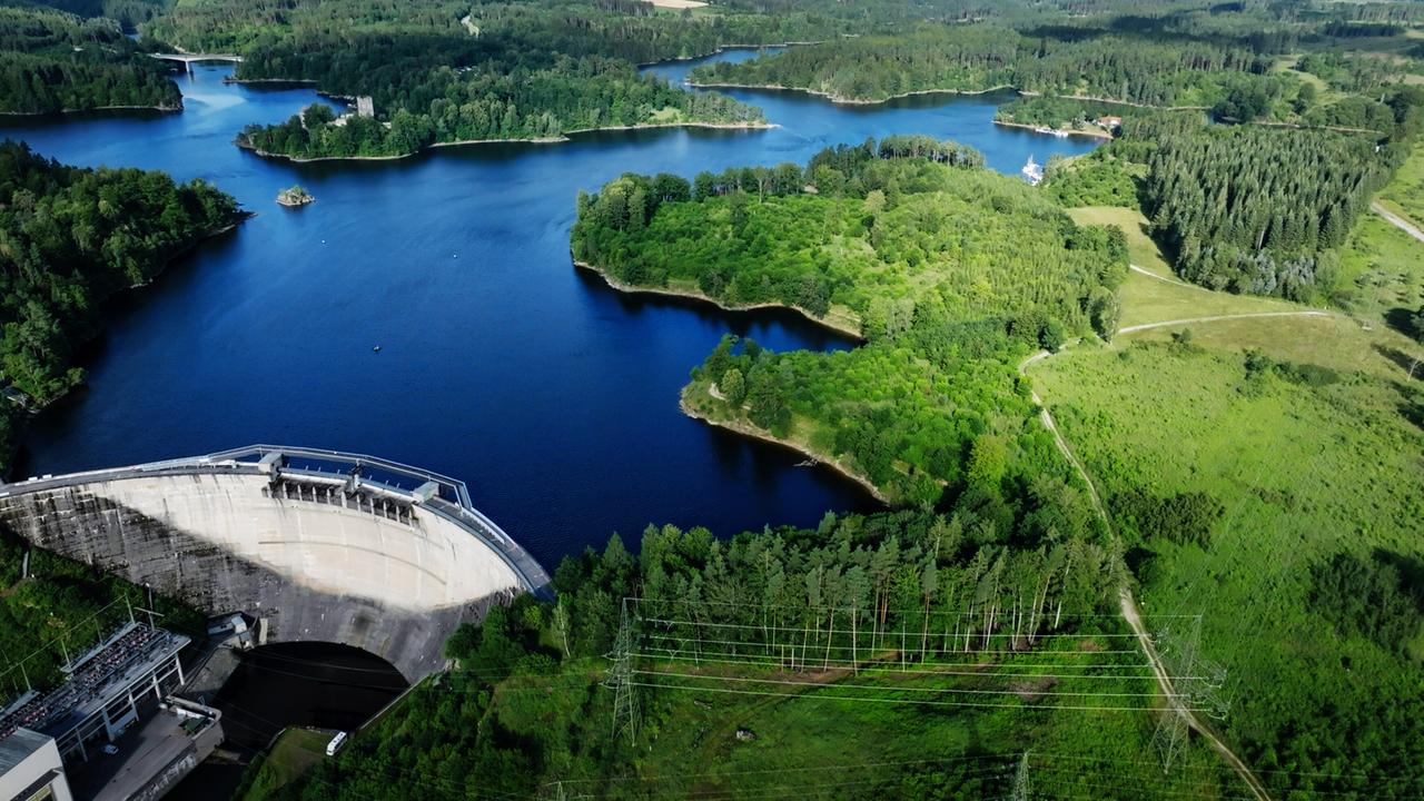Von oben ein tiefblauer See zwischen grünen Waldgebieten