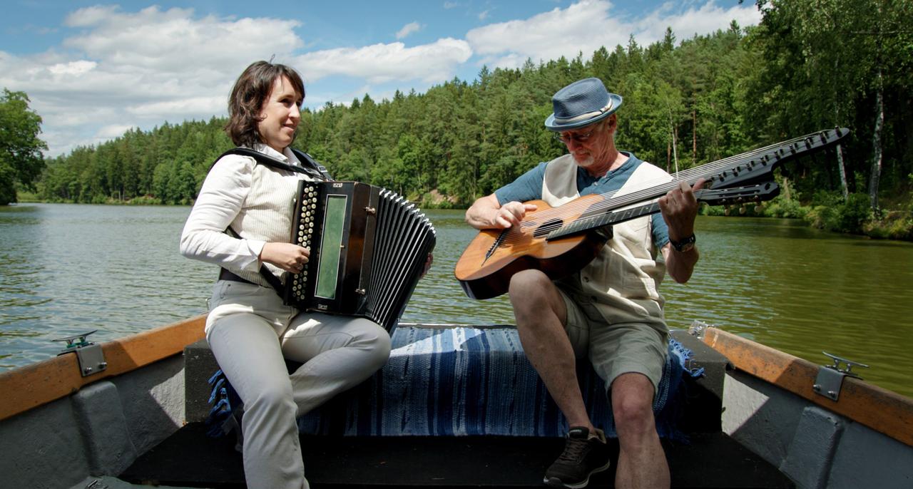 Ein Mann und eine Frau mit ihren Musikinstrumenten auf einem Boot