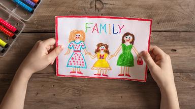 Eine bunte Kinderzeichnung, auf der zwei Frauen ein Mädchen in der Mitte an den Händen halten