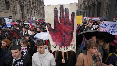 Demonstrationszug von jungen Leuten, vorne wird ein riesiges Plakat mit einer blutroten Hand hochgehalten.