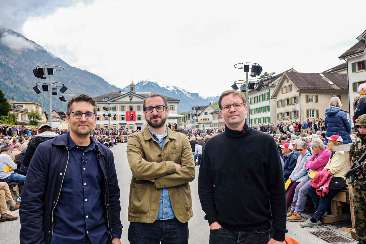 Drei Männer bei einer Versammlung 