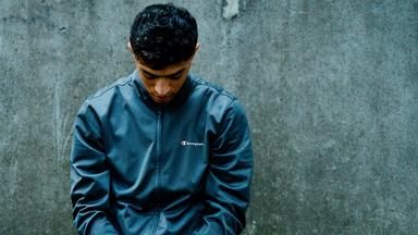 Ein junger Mann, dessen Hände mit Kabelbindern zusammengebunden sind.