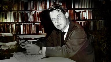  Der junge Siegfried Lenz sitzt vor einer Bücherwand am Schreibtisch (s/w). 