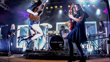 Zwei Rockmusikerinnen spielen E-Gitarre auf der Bühne.