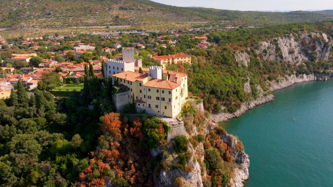 Ein Schloss auf einem hohen Felsen an einem See gelegen.