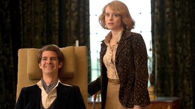 Ein Mann in einem altertümlichen Rollstuhl. Daneben eine junge Frau.