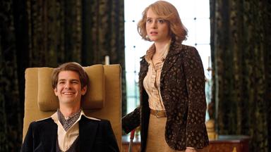 Ein Mann in einem altertümlichen Rollstuhl. Daneben eine junge Frau.