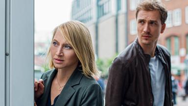 Frau und Mann schauen verstohlen um die Ecke.