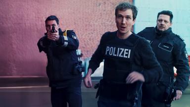 Simon (Jan Krauter) im Einsatz mit schusssicherer Polizeiweste. Hinter ihm zwei Kollegen.
