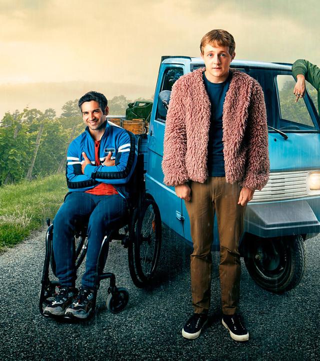 Zwei junge Männer und eine Frau stehen vor einem kleinen, dreirädrigen, blauen Auto der Marke Ape Piaggio.