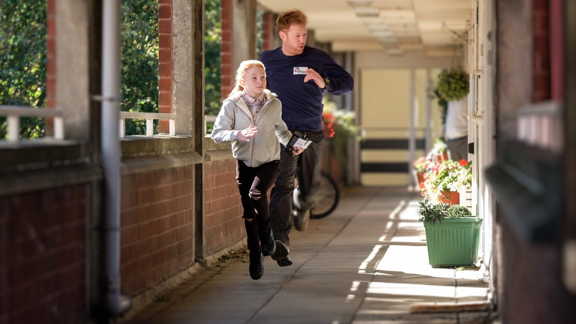 Mit skeptischem Blick schaut Ricky (Kris Hitchen) drein, als er zwischen verschiedenen weißen Lieferwagen steht.