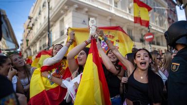 Menschen halten spanische Flaggen hoch und skandieren Parolen.