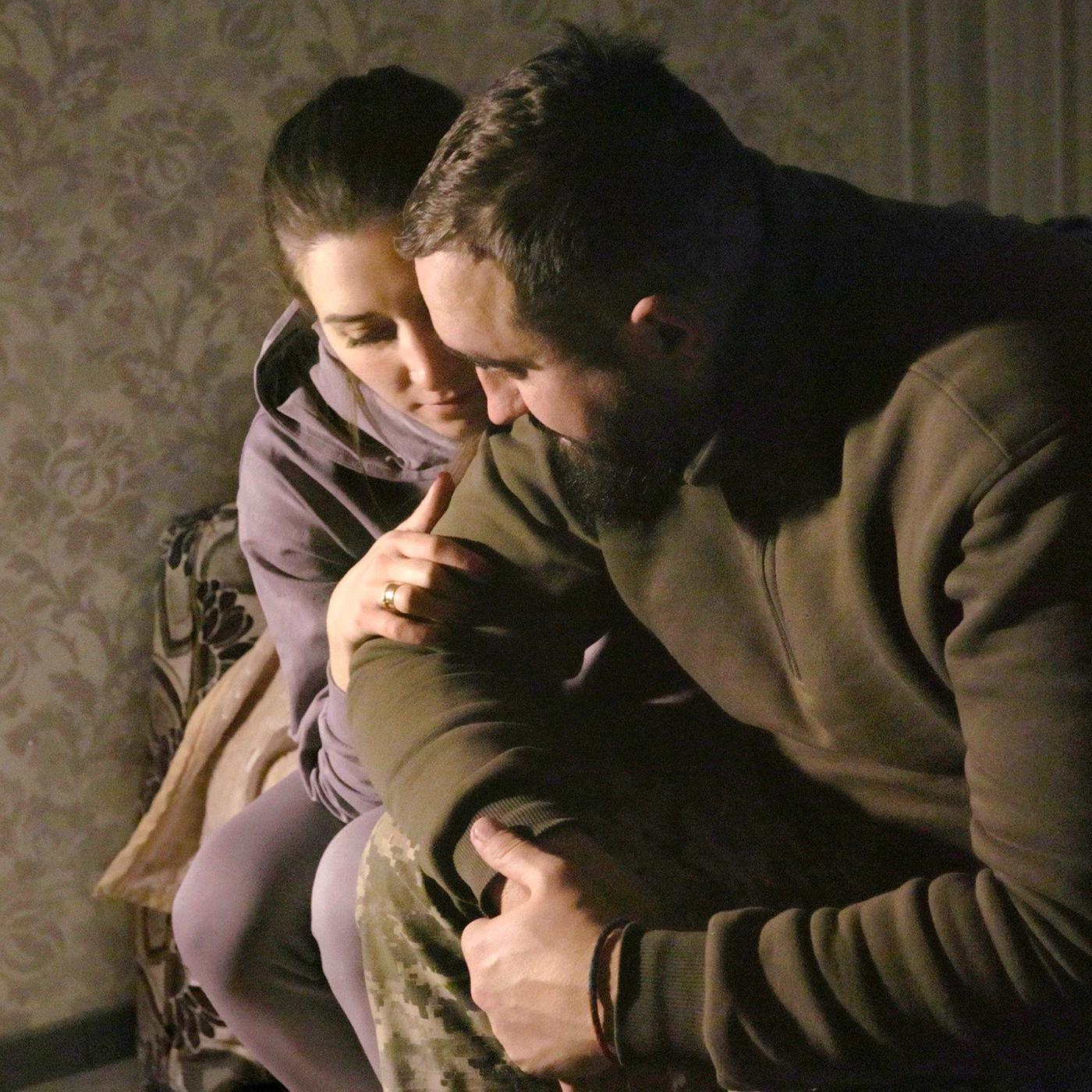 Ein Mann und eine Frau sitzen eng umschlungen auf einem Bett.