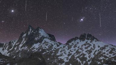 Sternschnuppen am  Nachthimmel über einem Gebirge.
