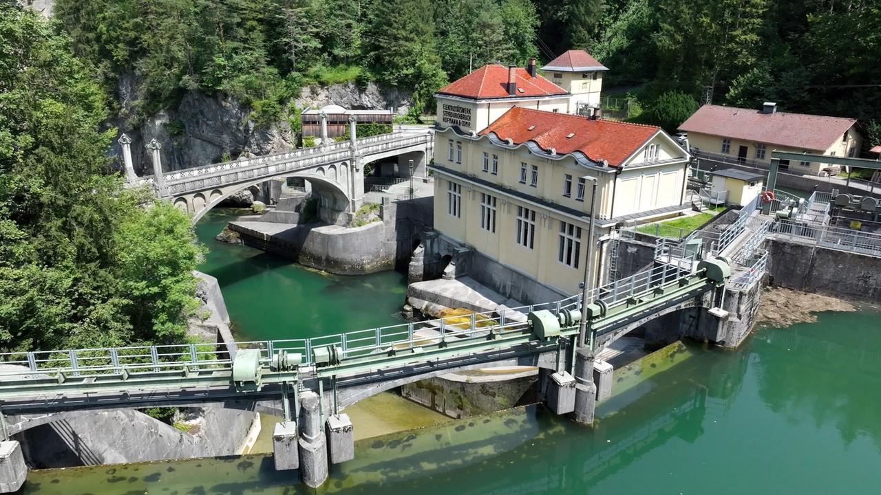 Historisches Wasserkraftwerk Steyrdurchbruch mit Stauanlage und Brücke, umgeben von Felsen und Wald, an einem türkisgrünen Fluss gelegen.