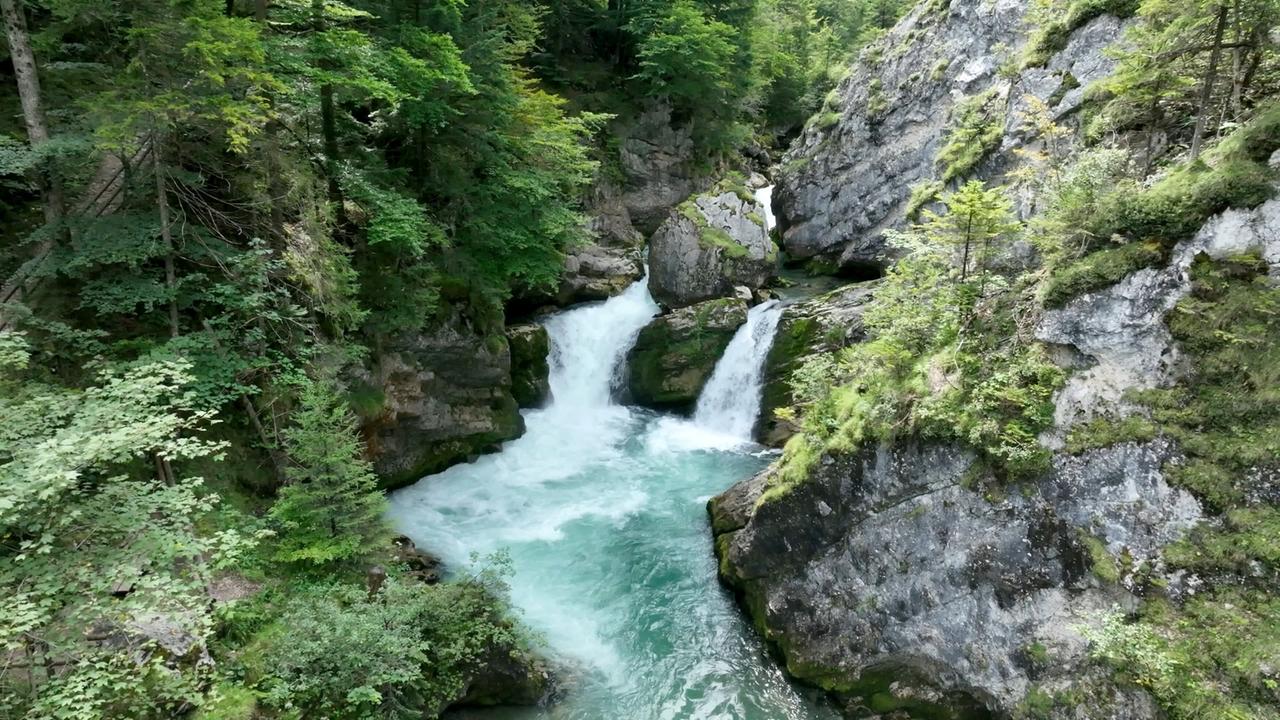 Wildromantischer Gebirgsfluss Steyr mit Wasserfällen und smaragdgrünem Wasser, eingebettet in eine bewaldete Schluchtlandschaft.