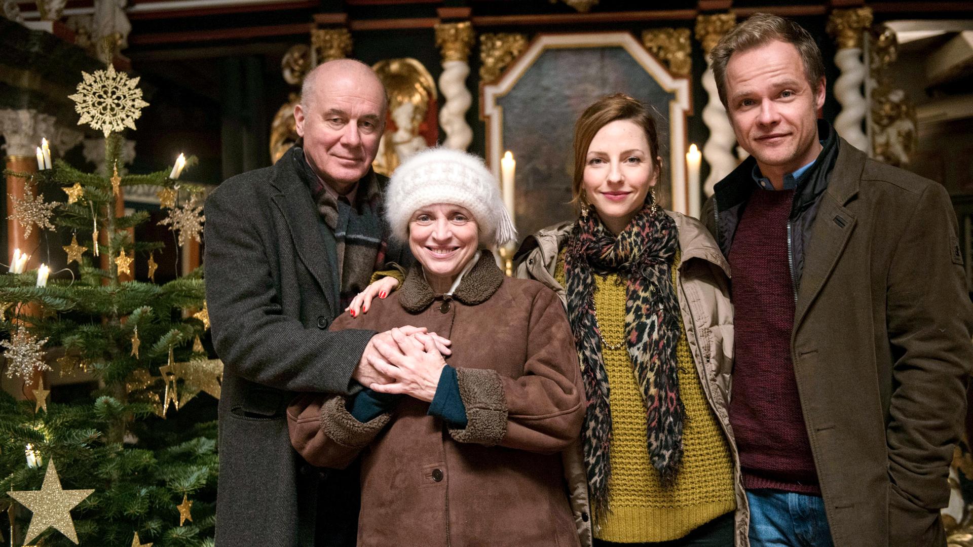 Zwei Frauen und zwei Männer in Winterkleidung neben einem Weihnachtsbaum