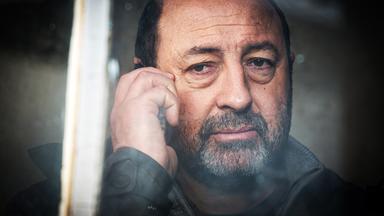 Bärtiger Mann telefoniert mit einem Handy.