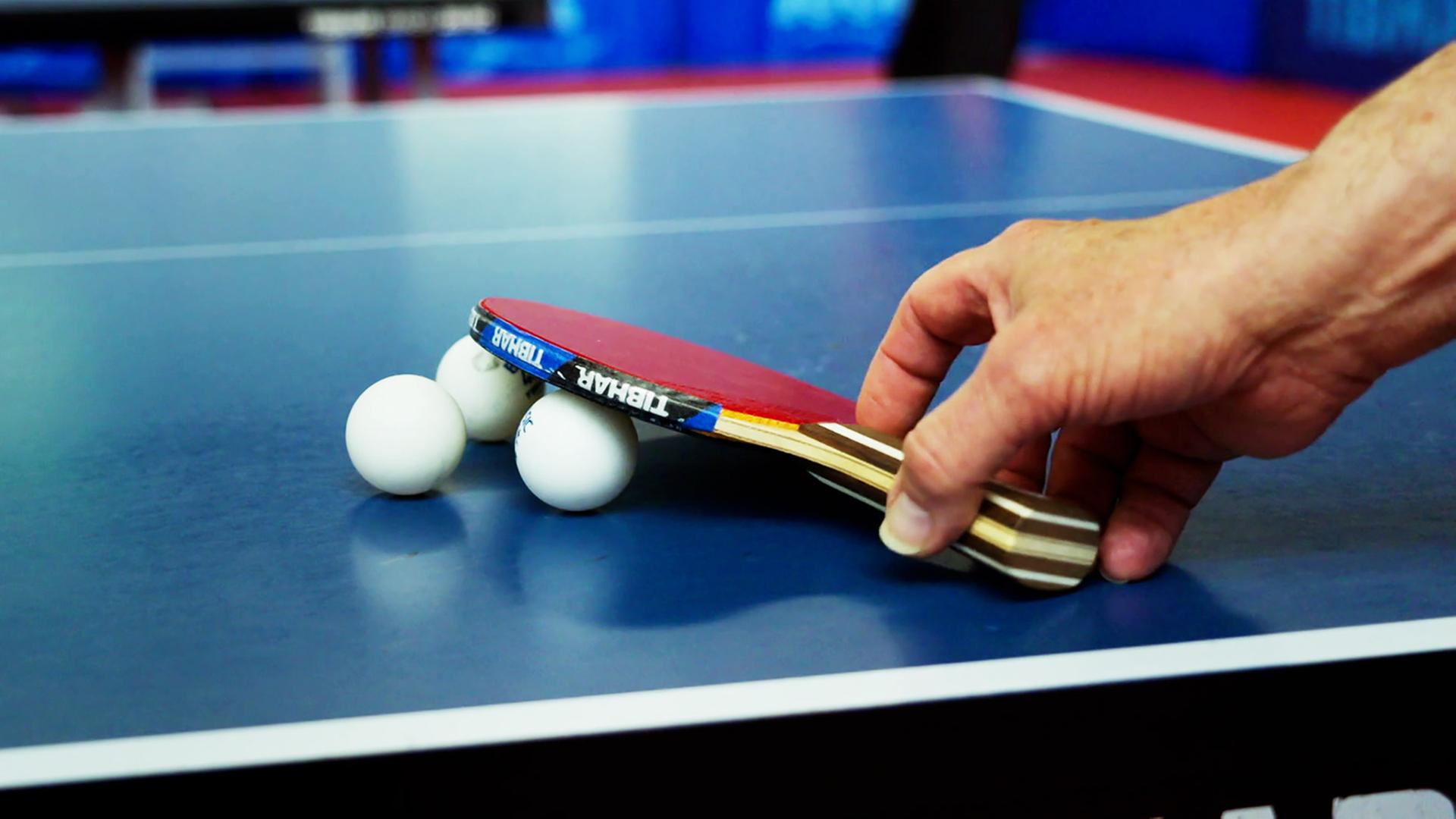 Hand greift nach Tischtennisschläger.