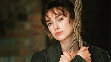 Das nahe Portrait einer jungen Frau, die hinter einem Strick hervorschaut.