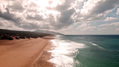 Weite Sandlandschaft von Scivu-Piscinas an der Costa Verde mit Dünen, Meer und bewölktem Himmel.