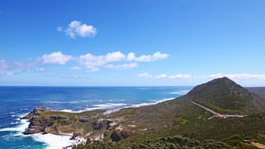 Blick von Cape Point auf das Kap der Guten Hoffnung mit schroffer Felsküste, hügeliger Landschaft und dem tiefblauen Meer.