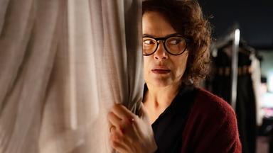 Eine Frau an einem Vorhang.