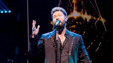 Ein Mann singt auf der Bühne. Im Hintergrund eine Band.