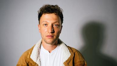 Ein junger Mann vor einer Wand.