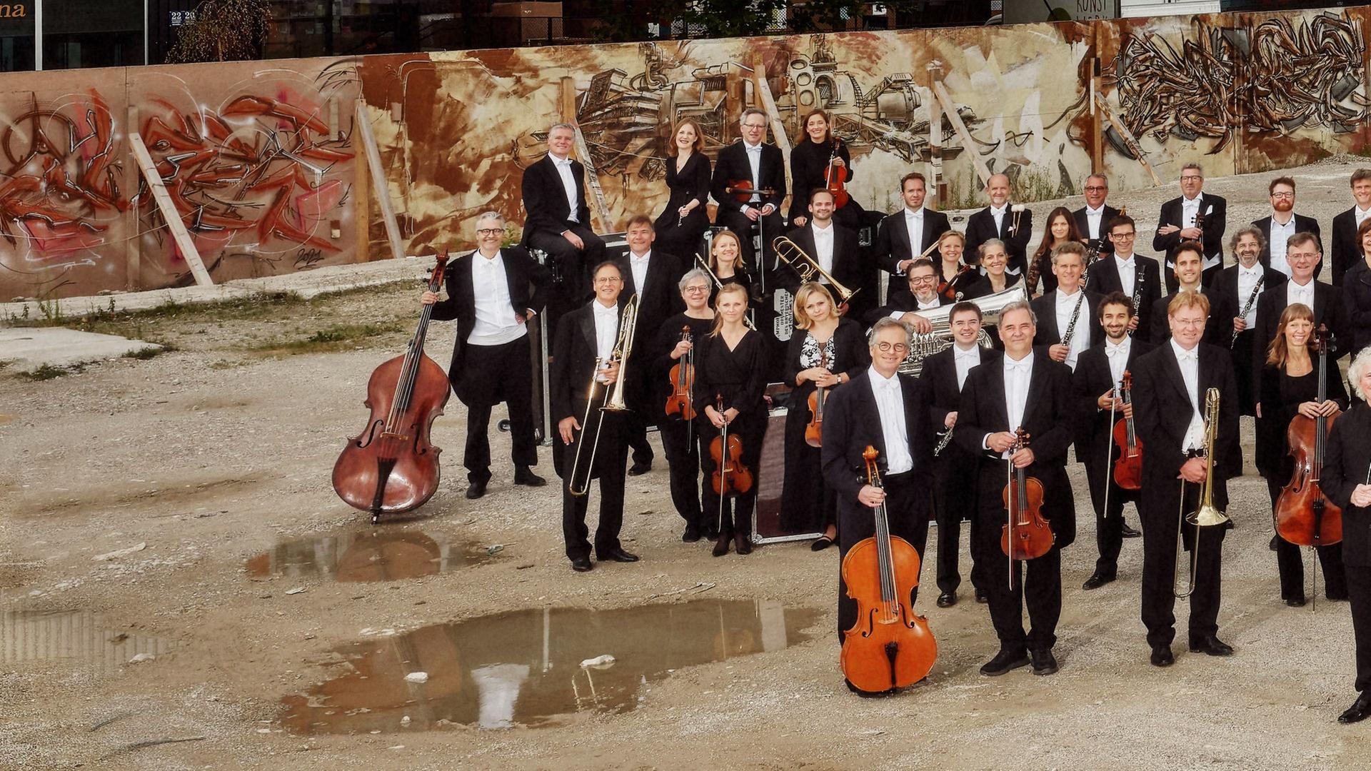 Musiker*innen mit ihren Instrumenten auf einem Schotterplatz.