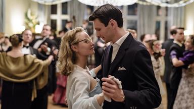 "Ku'damm 56 - Teil 3": Monika Schöllack (Sonja Gerhardt, mittig) und Freddy Donath (Trystan Pütter, rechts) tanzen auf dem Abschlussball der Tanzschule Galant Rock 'n' Roll. Um sie herum viele tanzende Menschen.