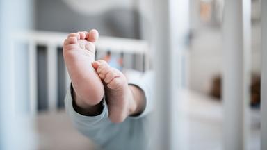 Ein Baby in einem Kinderbett. Symbolbild