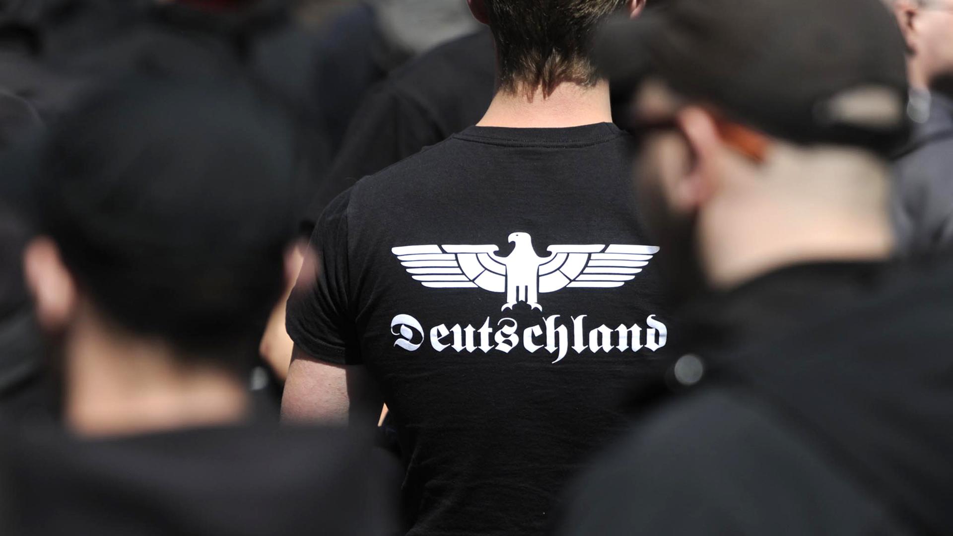 Auf einer rechtsextremen Demonstration trägt ein Neonazi ein T-Shirt mit stilisiertem Adlermotiv und der Aufschrift Deutschland.