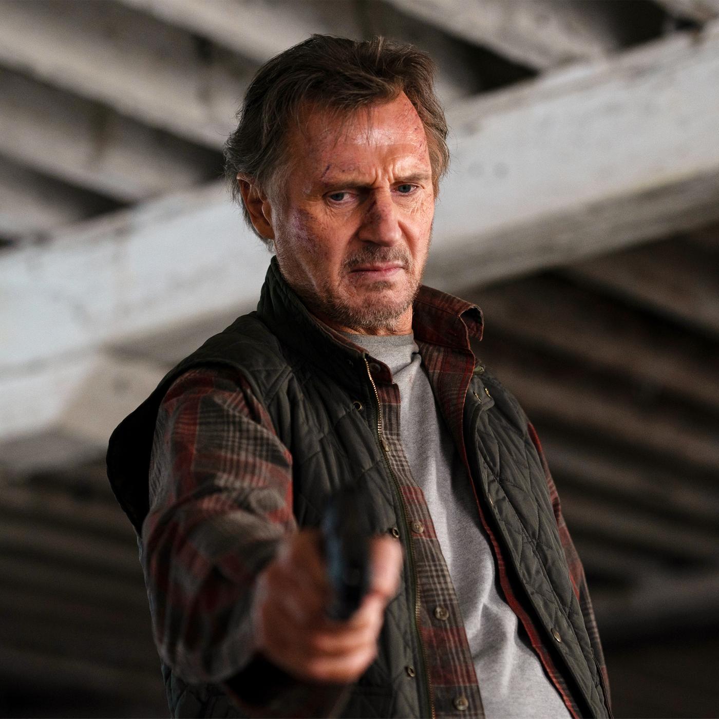 Jim Hanson (Liam Neeson) steht unter einer Brücke, hält eine Waffe in ausgestreckter Hand und blickt ernst nach unten.