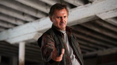 Jim Hanson (Liam Neeson) steht unter einer Brücke, hält eine Waffe in ausgestreckter Hand und blickt ernst nach unten.