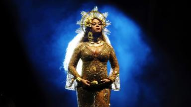 Beyonce tritt bei der Verleihung der 59. Grammy Awards auf. Sie trägt ein durchsichtiges goldenes Kleid und einen kronenartigen goldenen Schmuck auf dem Kopf.
