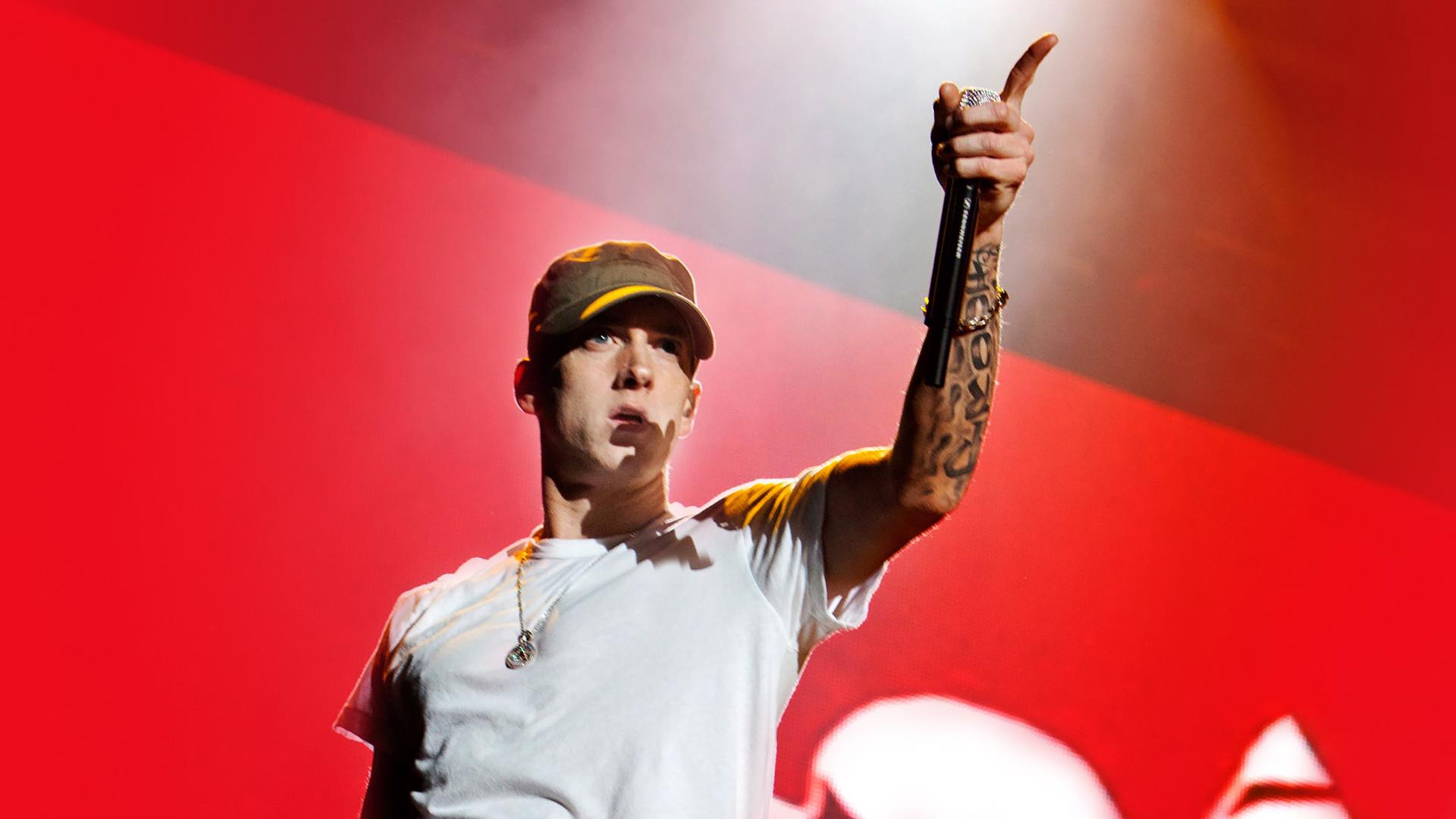 Eminem in einem weissen T-shirt vor einem roten Hintergrund
