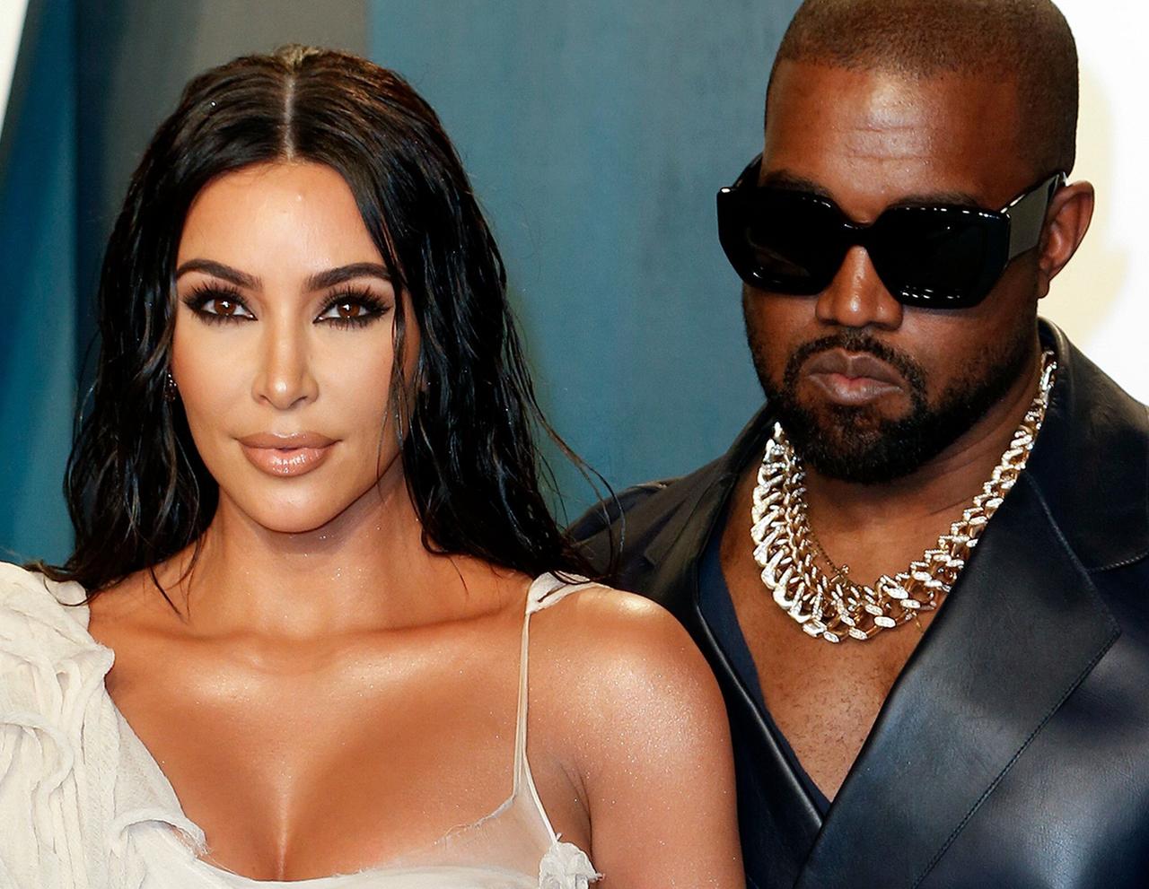 Kanye West, gekleidet mit einer schwarzen Jeans und einer blauen Jeansjacke, zusammen mit seiner damalighen Ehefrau Kim Kardashian, die ein silbernes Kleid trägt.