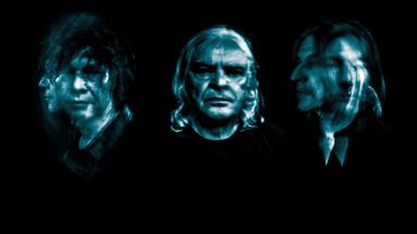 Drei Mitglieder der Band The Young Gods erscheinen in künstlerisch verzerrter Langzeitbelichtung auf schwarzem Hintergrund, was eine surreale, psychedelische Wirkung erzeugt.