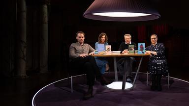 Um einen runden Tisch sitzen zwei Männer und zwei Frauen. Alle blicken in Richtung des Beobachters und vier Bücher stehen auf dem Tisch.