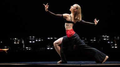 Bühnenszene: Eine Tänzerin tanzt in einem schwarz-roten Kostüm.