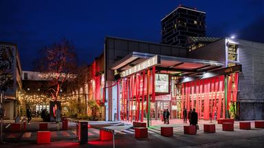Das Theaterhaus Stuttgart bei Nacht. Es ist festlichmit roten Banner geschmückt.
