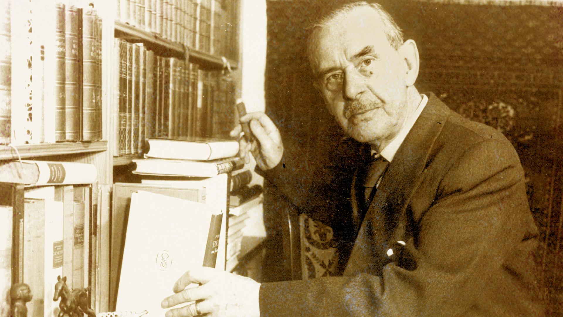 Schwarz-weiß-Bild eines älteren Mannes, ein Buch aus einem Bücherregal nimmt.