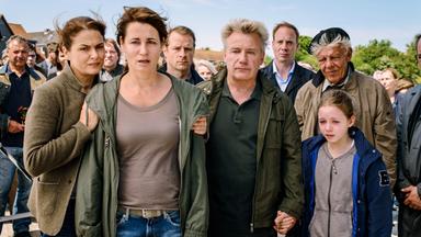 "Tod eines Mädchens (1)": Hella Christensen (Barbara Auer), Silke Broder (Anja Kling), Torben Broder (Hinnerk Schönemann), Hermann Broder (Peter Striebeck), Lars von Ahnefeld (Johann von Bülow), Hauke Broder (Jörg Schüttauf) und Charlotte Broder (Lilly Barshy) stehen verzweifelt zusammen und schauen in die gleiche Richtung. Im Hintergrund stehen noch viele weitere Menschen.
