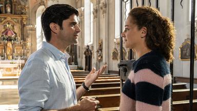 "Tonio & Julia - Ein neues Leben": In einer Kirche stehen sich Julia Schindel (Oona Devi Liebich) und Tonio Niederegger (Maximilian Grill) gegenüber und reden miteinander.