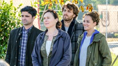 "Tonio & Julia: Schulden und Sühne": Im Freien stehen Tonio Niederegger (Maximilian Grill), Heike Sager (Bettina Mittendorfer), Guido Bender (Frederik Götz) und Julia Schindel (Oona Devi Liebich) dicht beieinander und blicken in die gleiche Richtung. Julia lächelt.